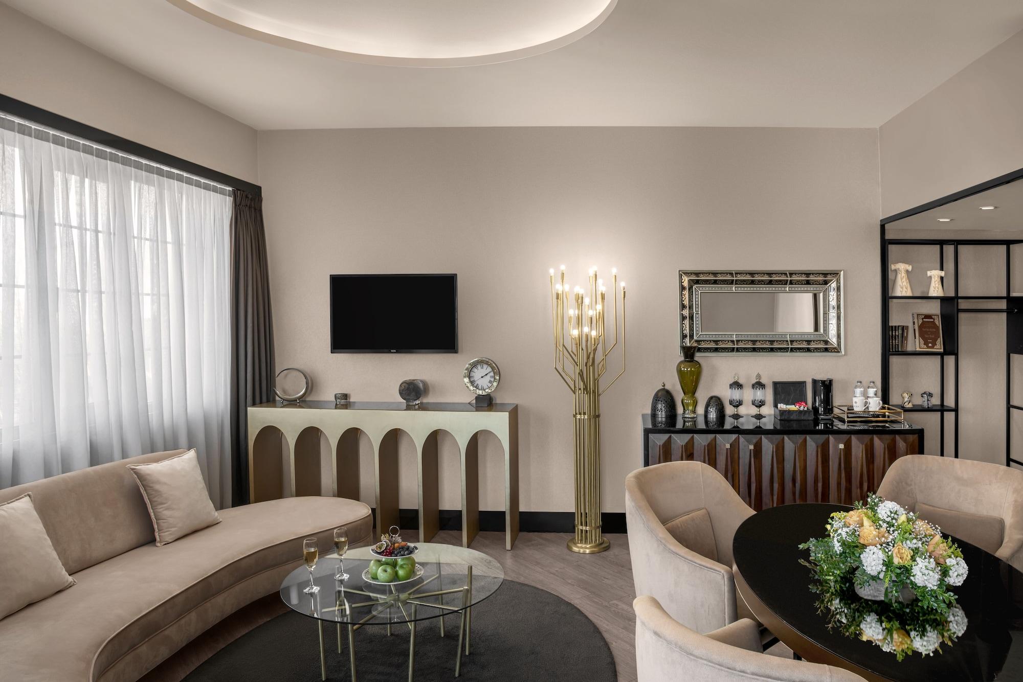 Sura Hagia Sophia Hotel Istanbul Exteriör bild The photo displays a stylish living room with modern decor. 

- **Seating Area:** There is a curved beige sofa and a round glass coffee table in the center.
- **Wall and Furnishings:** The walls are painted in a light color, with large windows dresse